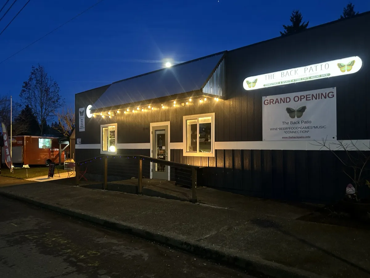 The Back Patio at dusk with the illuminated sign, string lights, and food cart